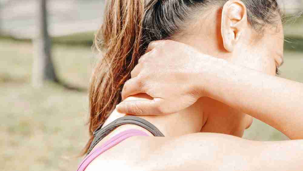 a close up shot of a woman rubbing her neck