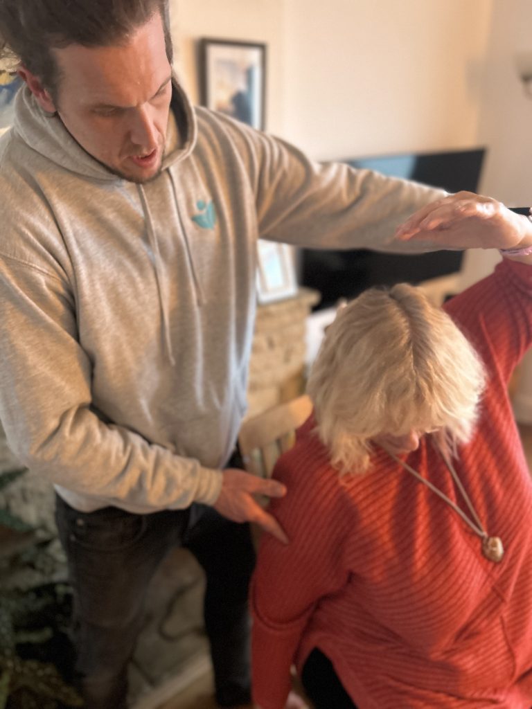 Physio Tom is adjusting Julie as she does a side stretch