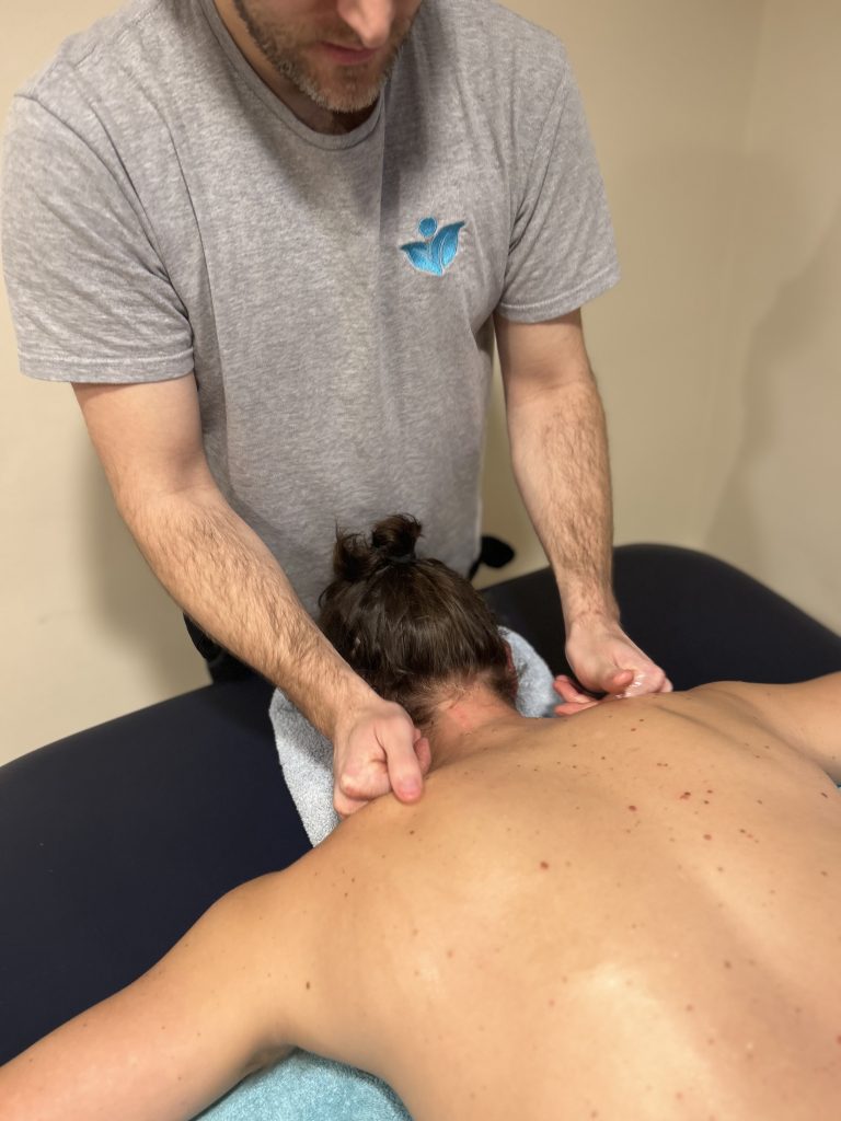 close up image of hands massaging shoulders of a man laying facedown