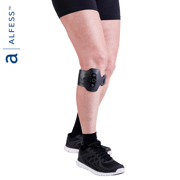 image of a pair of white legs wearing the device - a grey electronic device with arrow buttons and a grey strap